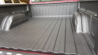 Black spray-on bed liner installed on red truck